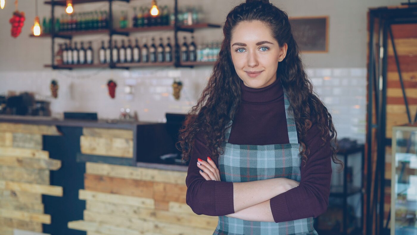 Young cafe owner standing proudly in her coffee shop